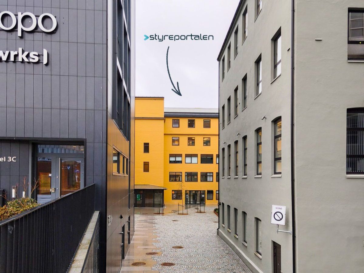 Bilde av gult hus innerst i en gate, sort pil med Styreportalens logo peker til øvre del av bygget